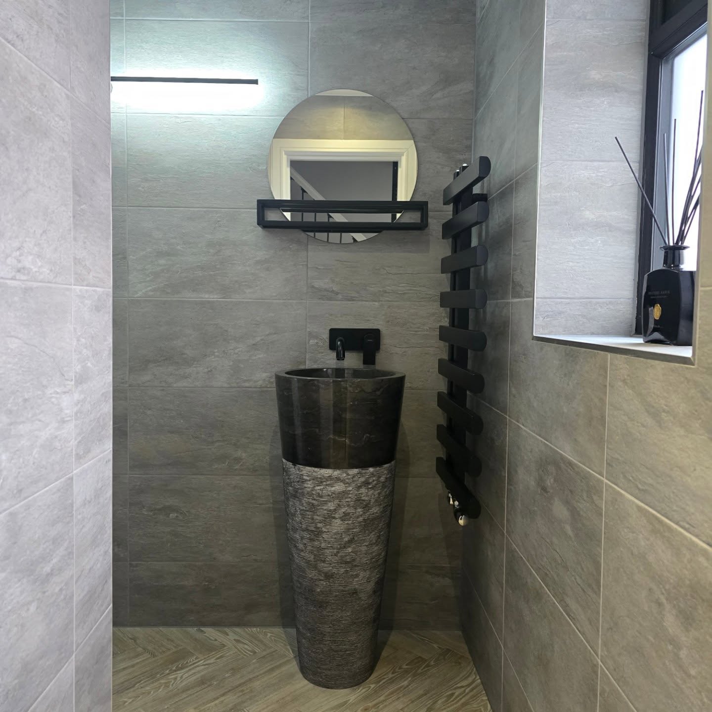 Modern grey cloakroom with sculptural basin and black towel rail