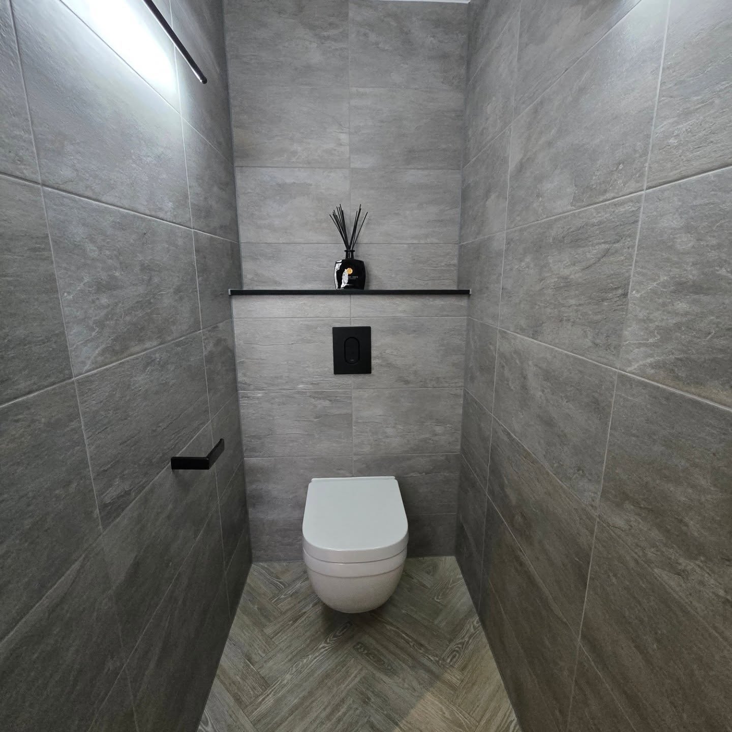 Modern grey cloakroom with wall-hung toilet and herringbone floor