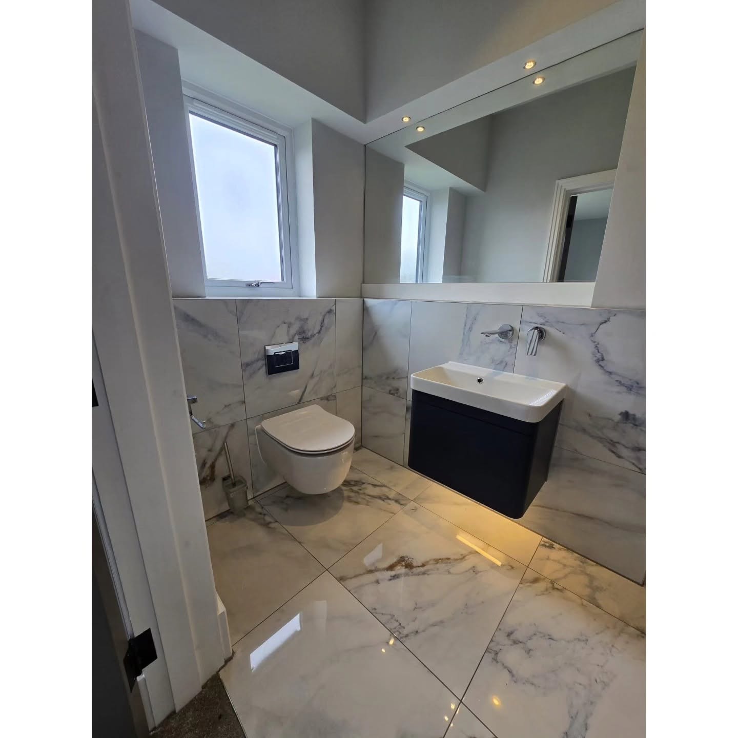 Completed marble bathroom with floating vanity and concealed toilet