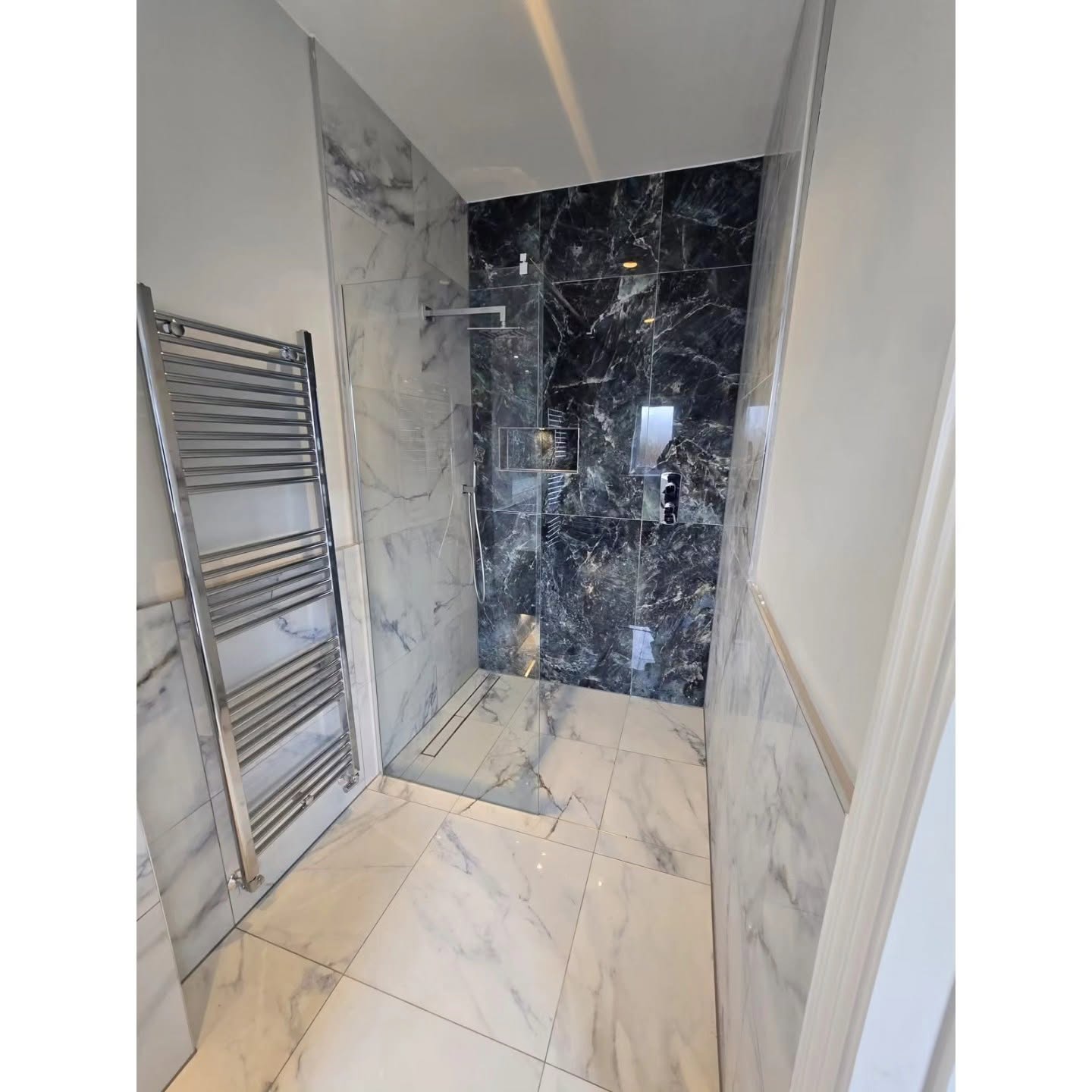 Walk-in marble shower with dark feature wall