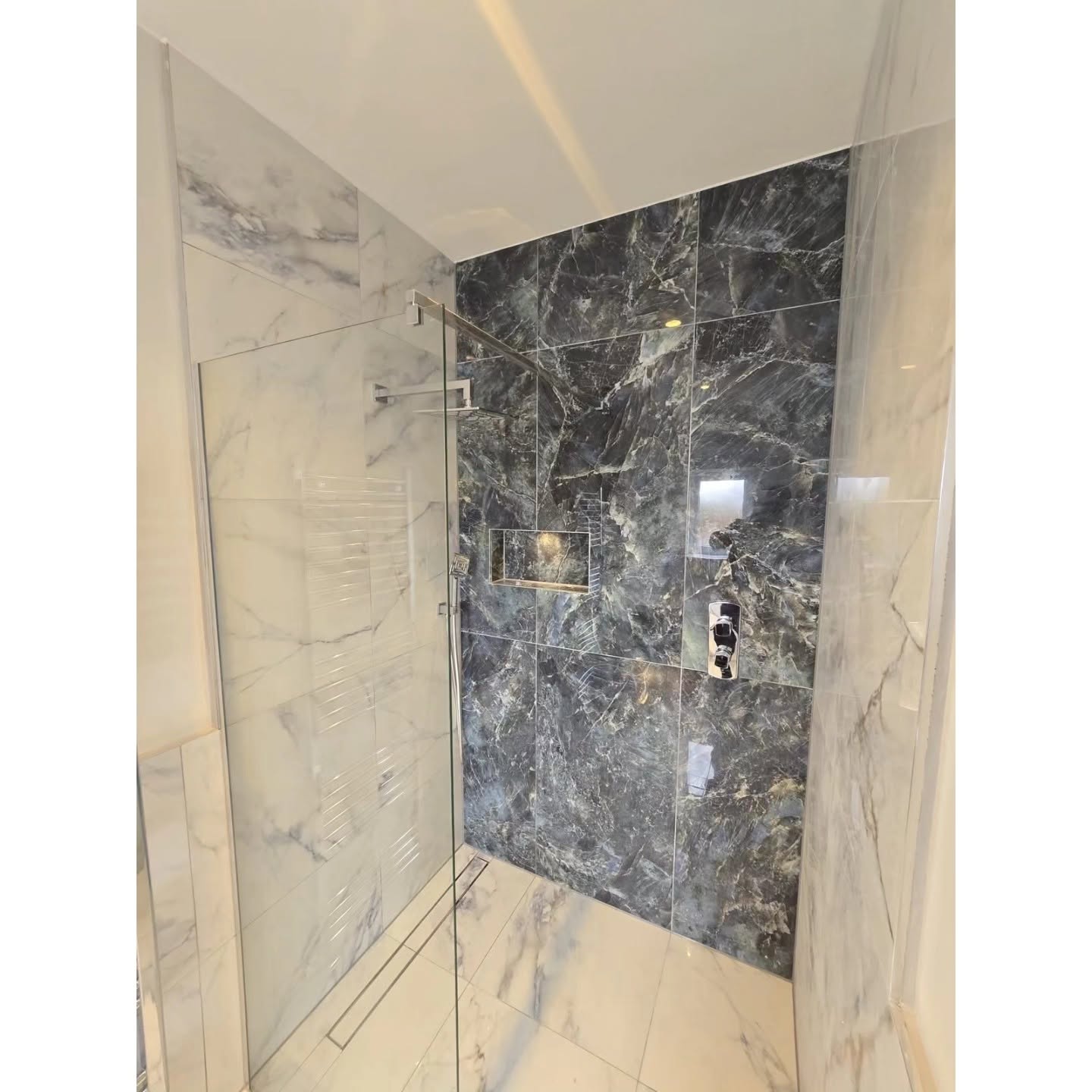 Detailed view of the marble walk-in shower and recessed shelf