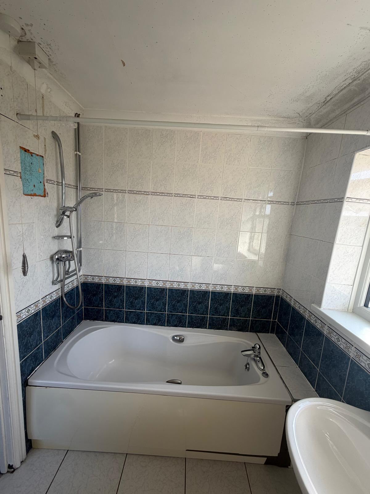 Dated blue and white tiled bathroom before renovation